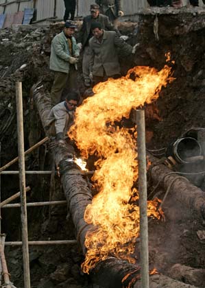 Workers repair a section of a natural gas pipeline in southwestern China's Chongqing municipality January 9, 2007. The pipeline was damaged when the road caved in, cutting off gas supply to about 300,000 people for seven hours, local media reported. Picture taken January 9, 2007. 
