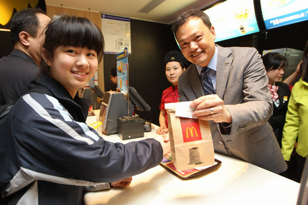 Kenneth Chan,CEO of McDonald's China hands over a bag of Egg McMuffinTM to a customer in a McDonald restaurant in Hangzhou city, East China's Zhejiang province on March 18, 2013, the date of National Breakfast Day. What's news